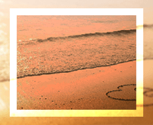 A heart drawn in the sand at a beach during sunset, with gentle waves lapping at the shore, conveying a romantic and serene atmosphere.