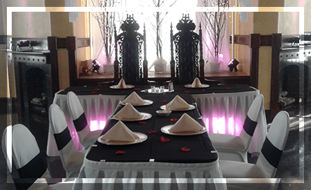 Elegantly set dining area featuring black and white tablecloths, neatly arranged plates, and decorative napkins, ideal for special events.