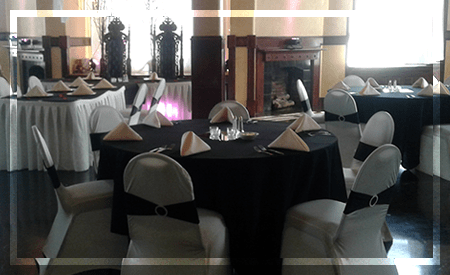 Elegantly set dining room featuring round tables draped in black and white linens, surrounded by stylish chairs, ready for an event or gathering.